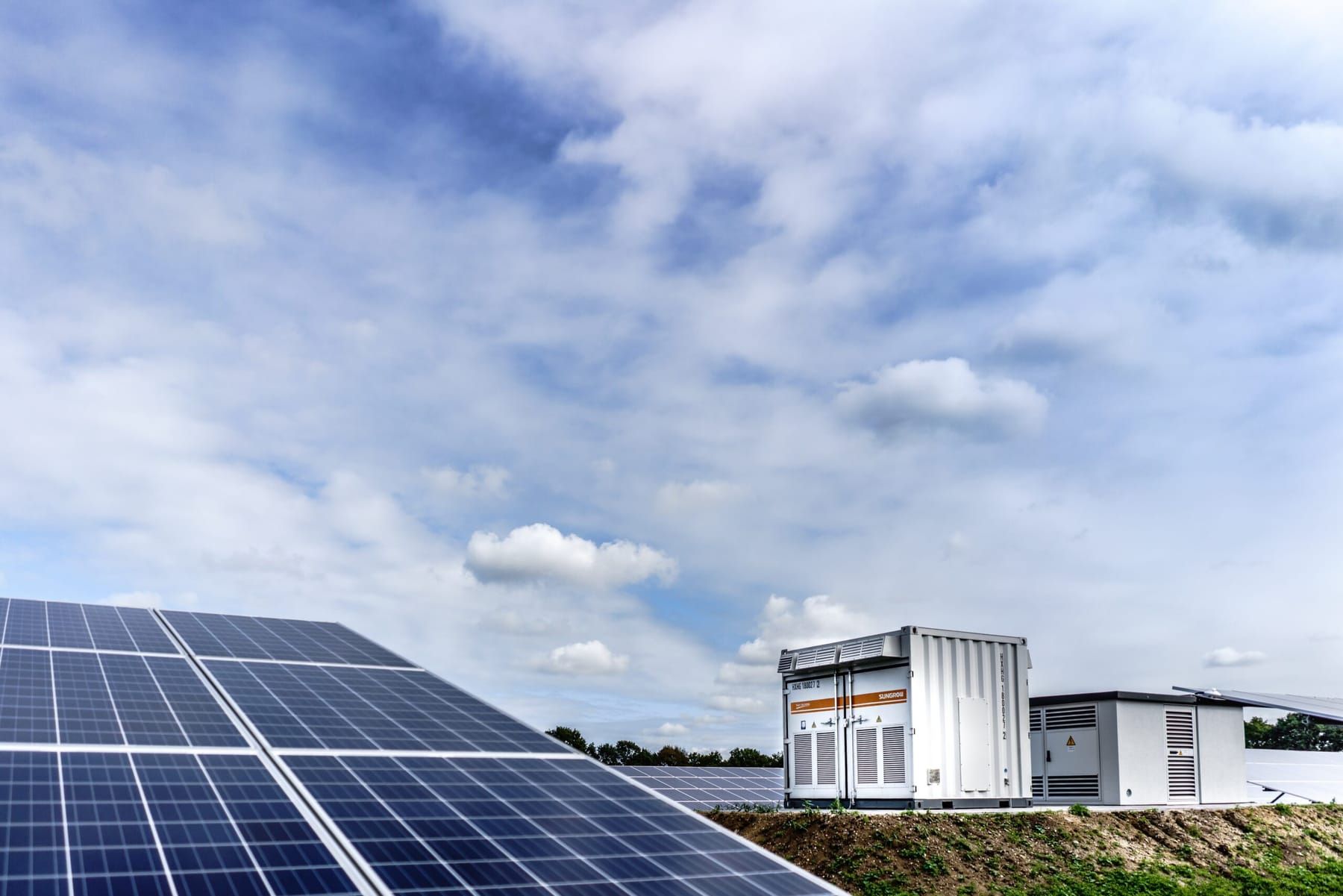 Batterijcontainer en transformatorhuis op een talud naast een zonnepark